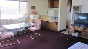 Un espacio habitable compacto con kitchenette, comedor, televisor y sofá.