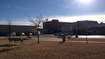 A parking lot with several cars, a bench, and a building with a sign that reads "Oscar's Printing".