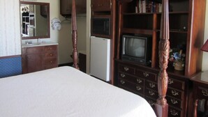 Un dormitorio con cama con dosel, armario de madera y televisor.
