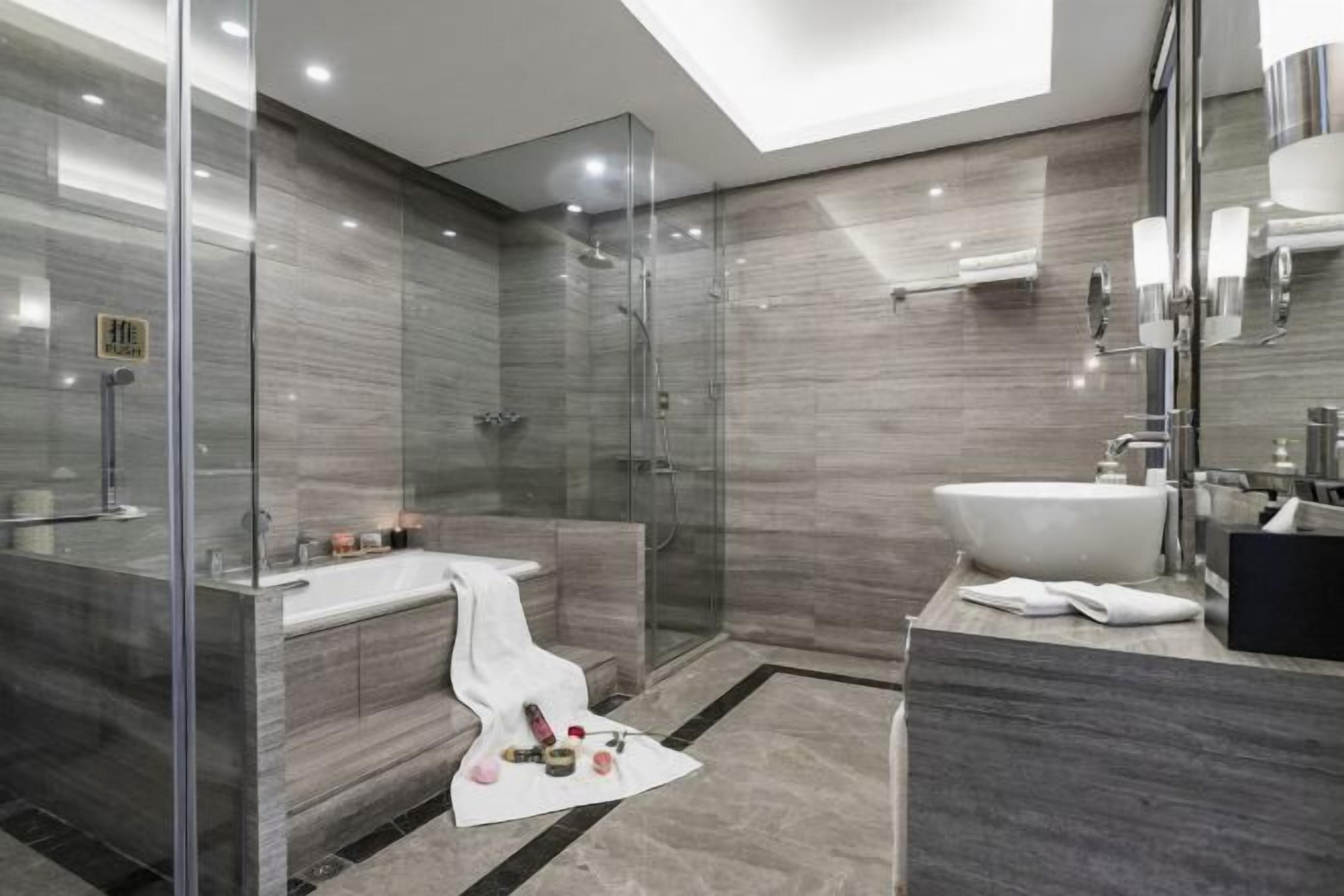Un baño moderno con ducha de vidrio, bañera independiente y un amplio lavamanos.