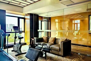 A modern hotel room with a treadmill, a sofa, and a glass partition. - Jiangyin Furen Boutique Hotel (Zhongshan Park Subway Station) (Jiangyin)