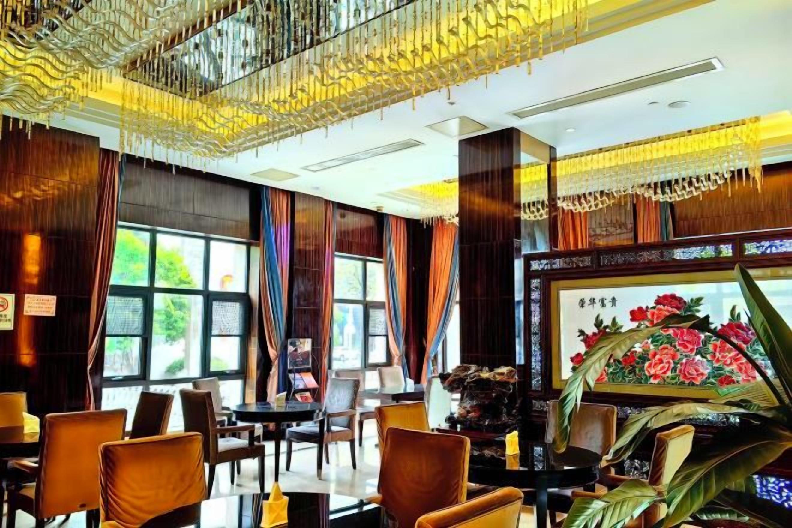 Un vestíbulo de hotel con candelabro, zona de estar y un ventanal con cortinas.