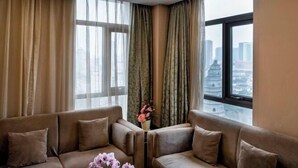 A modern hotel room with a large window, a sofa, and a vase with flowers. - Jiangyin Furen Boutique Hotel (Zhongshan Park Subway Station) (Jiangyin)