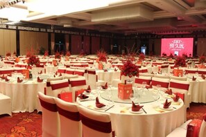 A banquet hall with round tables, red and white decor, and a stage with a pink screen. - Jiangyin Furen Boutique Hotel (Zhongshan Park Subway Station) (Jiangyin)