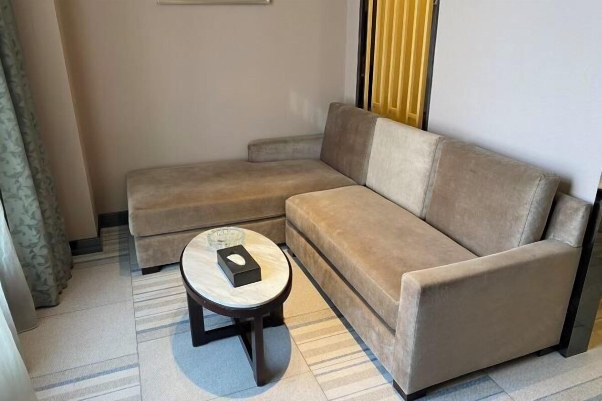 A beige sectional sofa with a small round table in front.