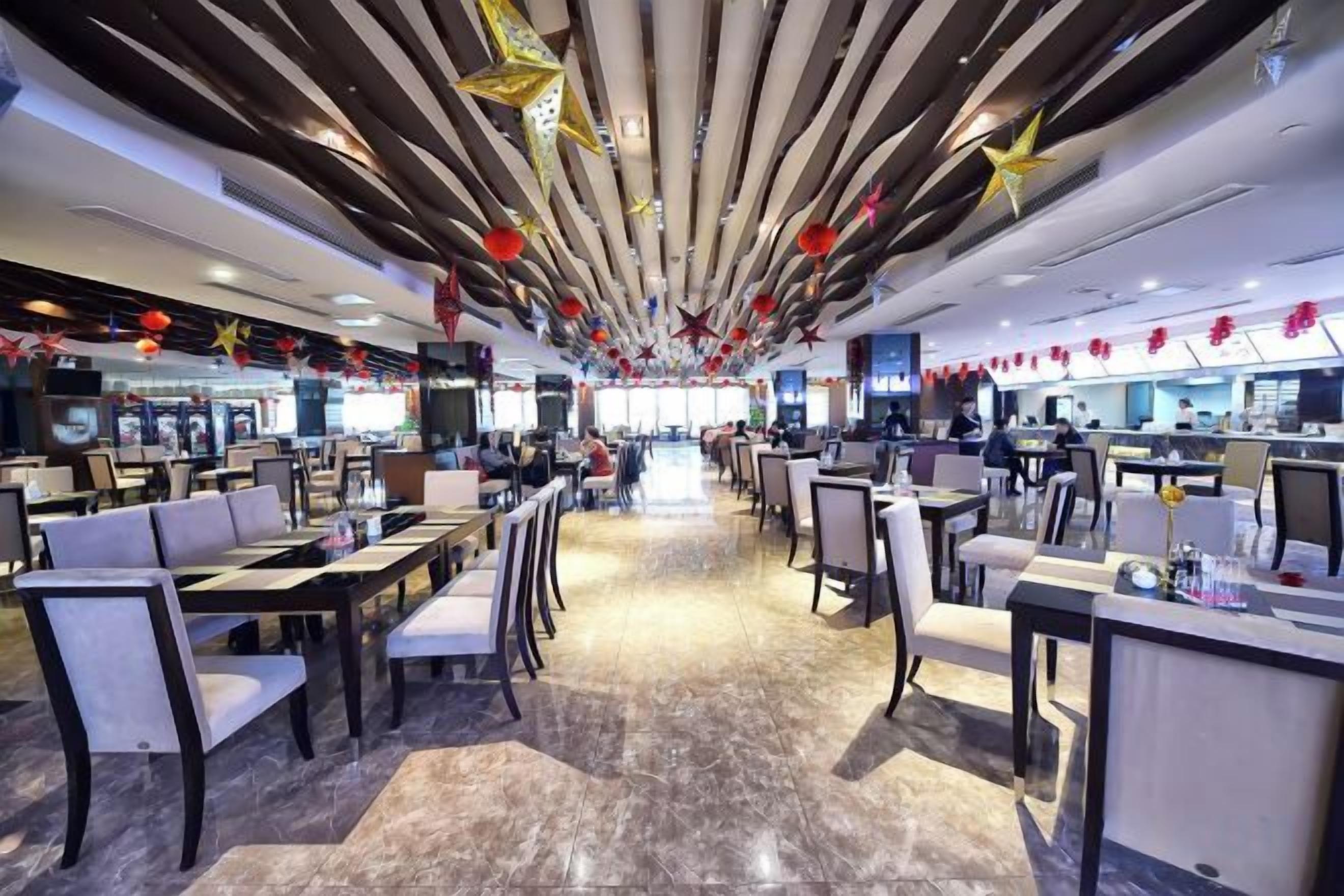 Un restaurante espacioso con techos altos, iluminación moderna y un pasillo central.