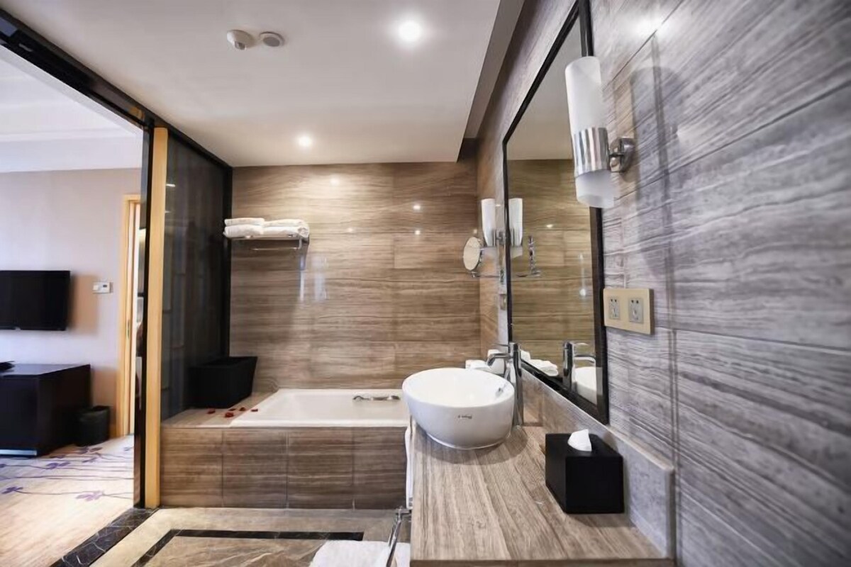 A modern bathroom with a bathtub, a round sink, and a large mirror.