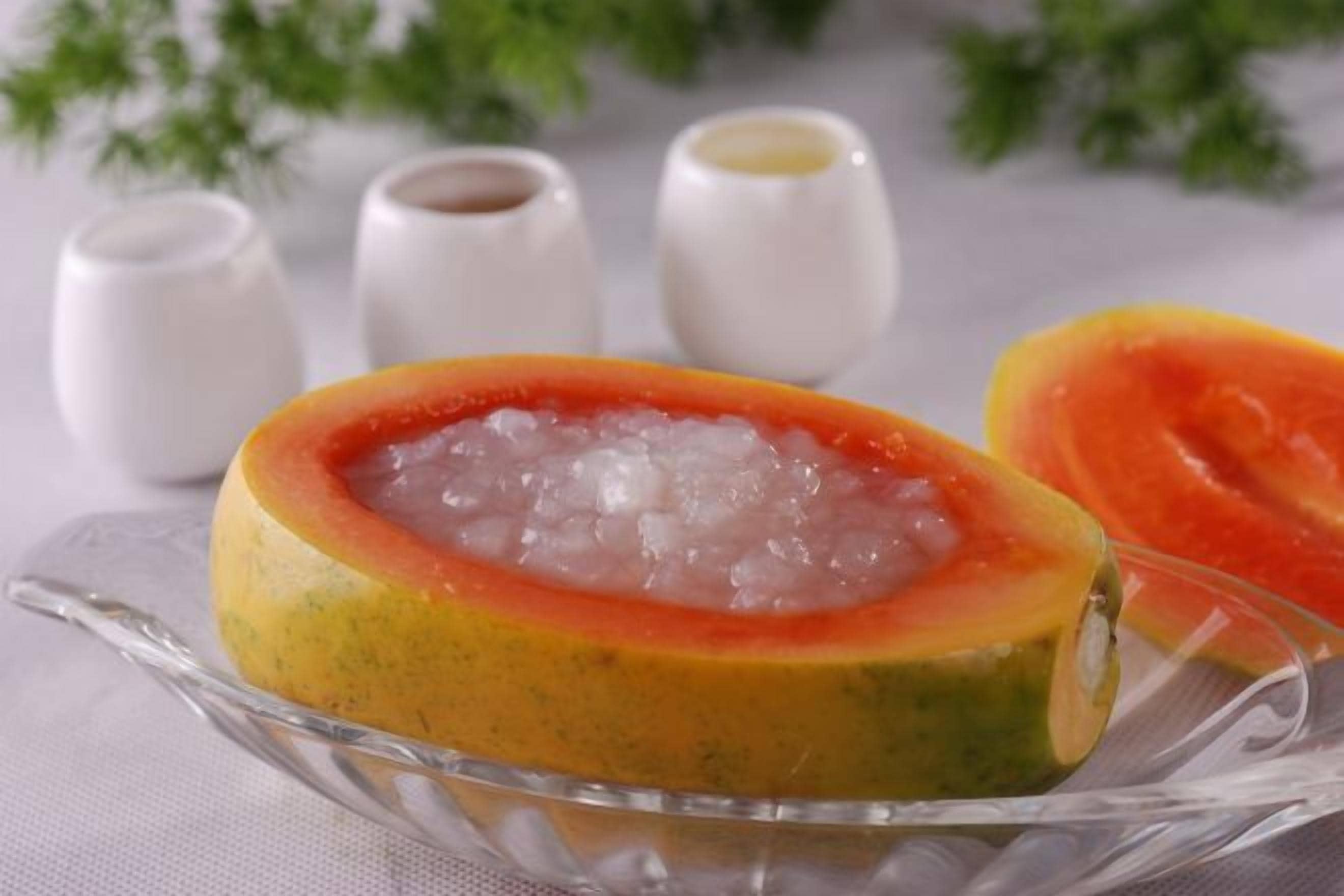 A papaya with its seeds removed, placed on a glass plate.