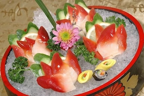 Een schotel sushi met verschillende soorten vis en garneringen, gepresenteerd op ijs.
