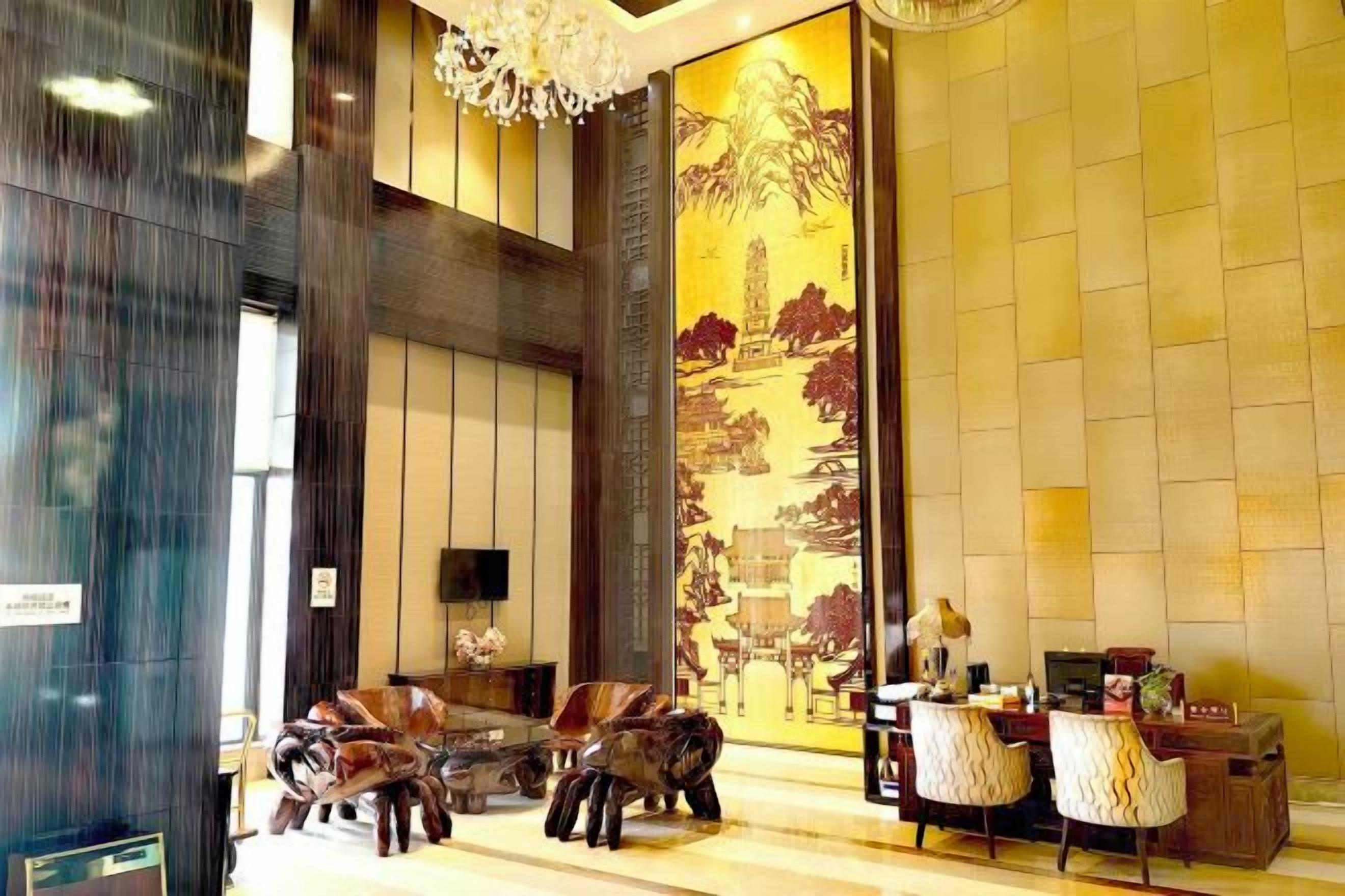 A lobby with a reception desk, seating area, and a large decorative wall.