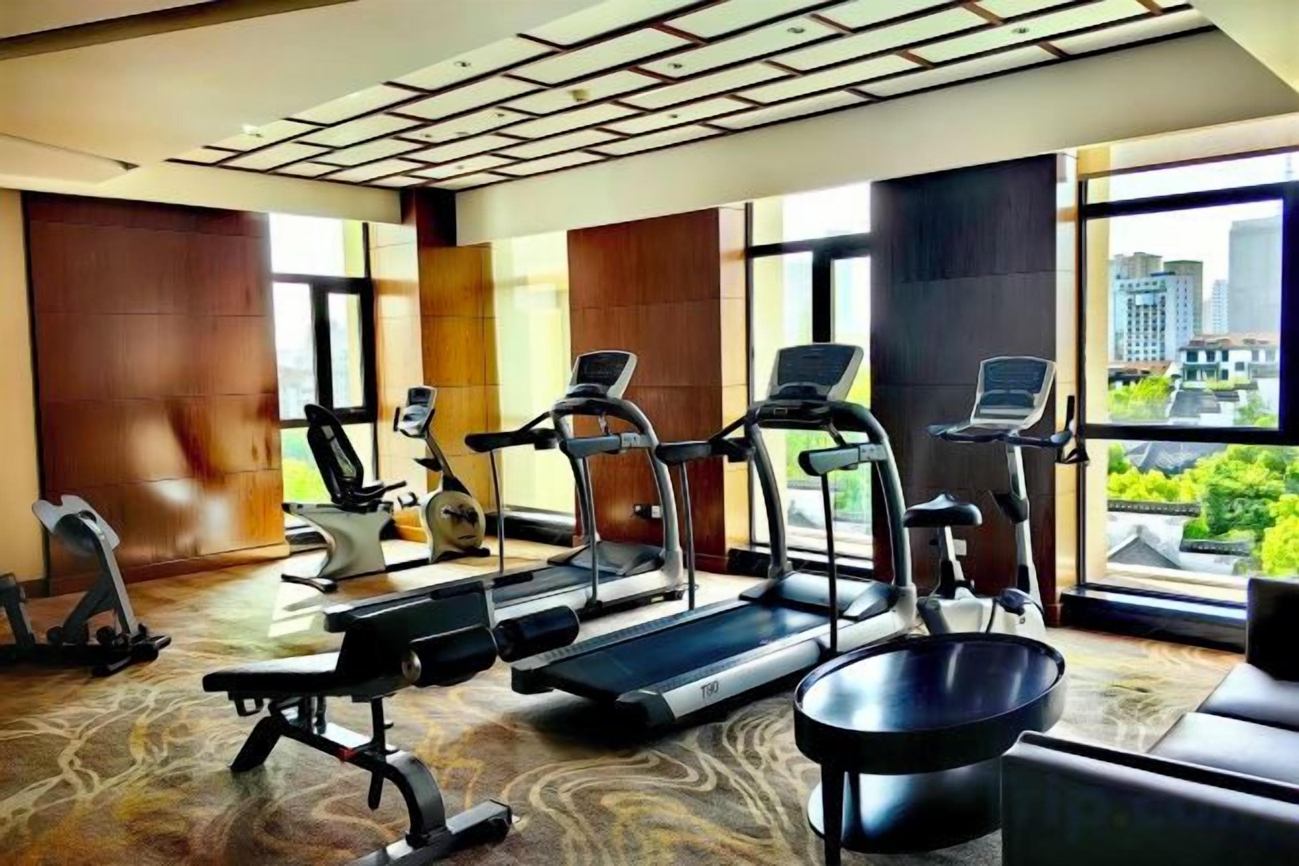 Un gimnasio con cintas de correr, bicicletas estáticas y una máquina de remo.