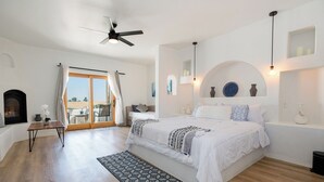 A bedroom with a bed, a ceiling fan, a fireplace, and a view through a glass door. - Sirena Resort (Paso Robles)