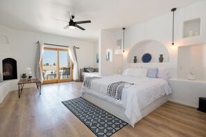 A bedroom with a bed, a ceiling fan, a fireplace, and a view through a glass door. - Sirena Resort (Paso Robles)