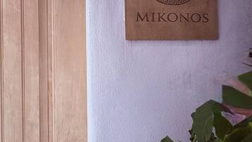 Eine Holztür, ein an der Wand befestigtes Schild mit Monogramm und Namen sowie ein Wandintercom.