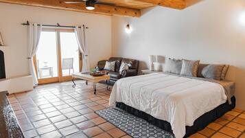 Quarto com cama, sofá, mesa e janela com cortinas.