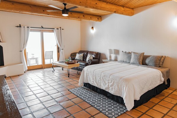 A bedroom with a bed, a sofa, a table, and a window with curtains.