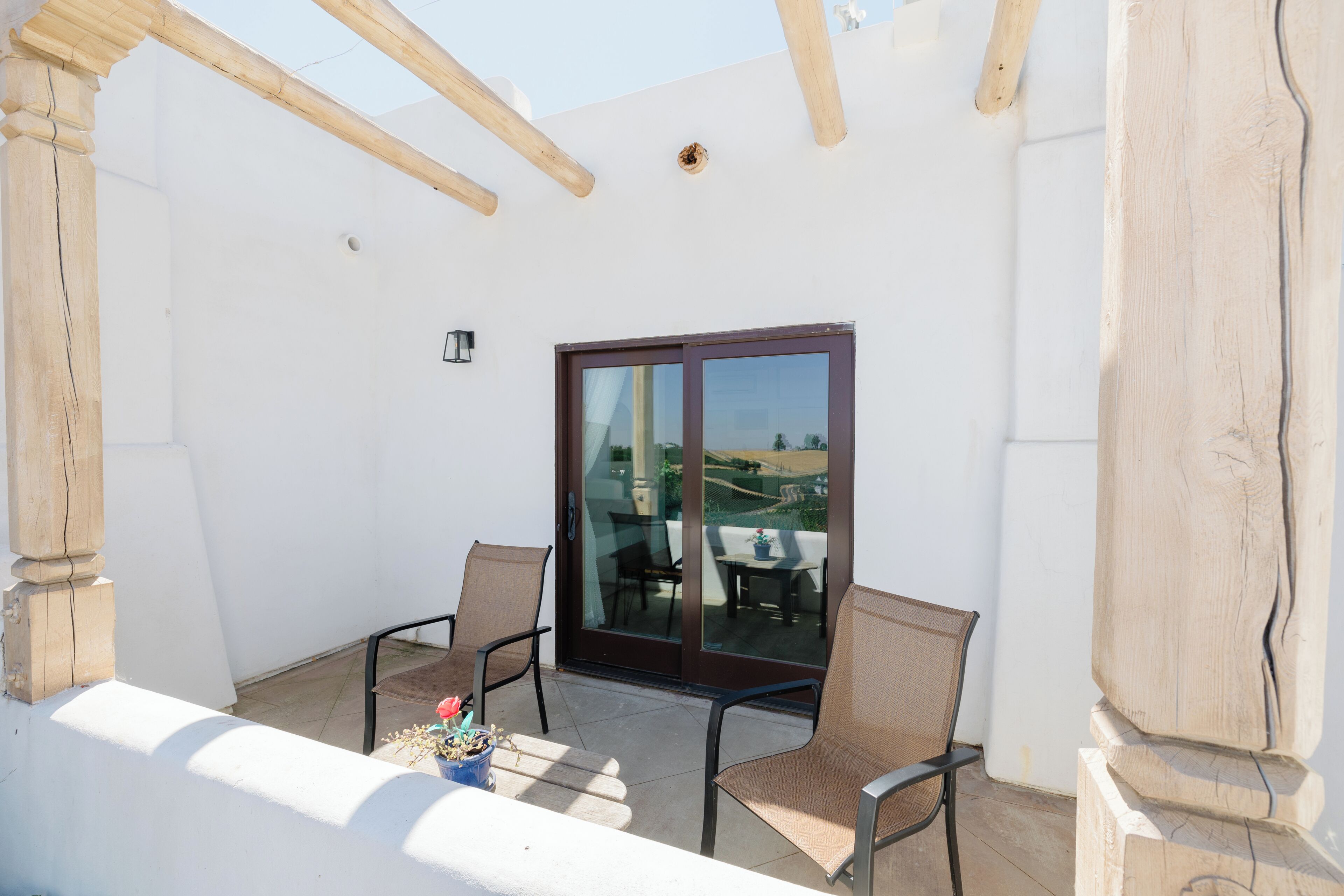 Een balkon met twee stoelen, een tafel en een schuifdeur naar een buitenruimte.