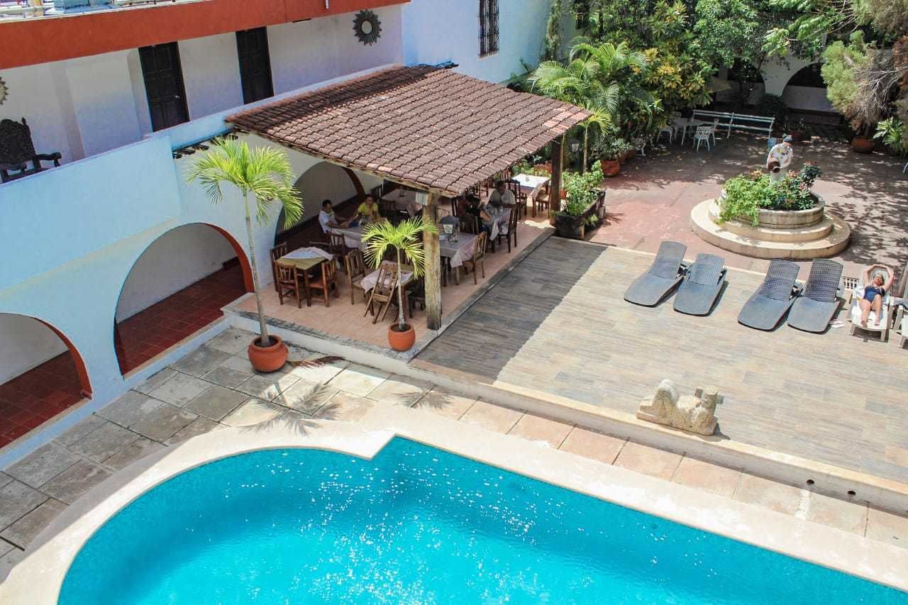 Zona de piscina con área de estar cubierta, sillones de descanso y un jardín circular.