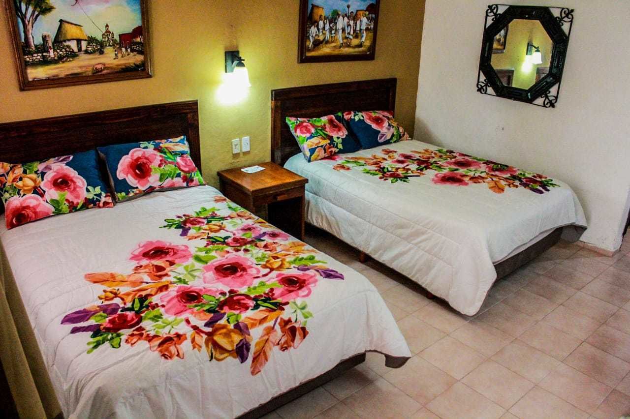 Two single beds with floral bedding, a nightstand, and a wall-mounted mirror.