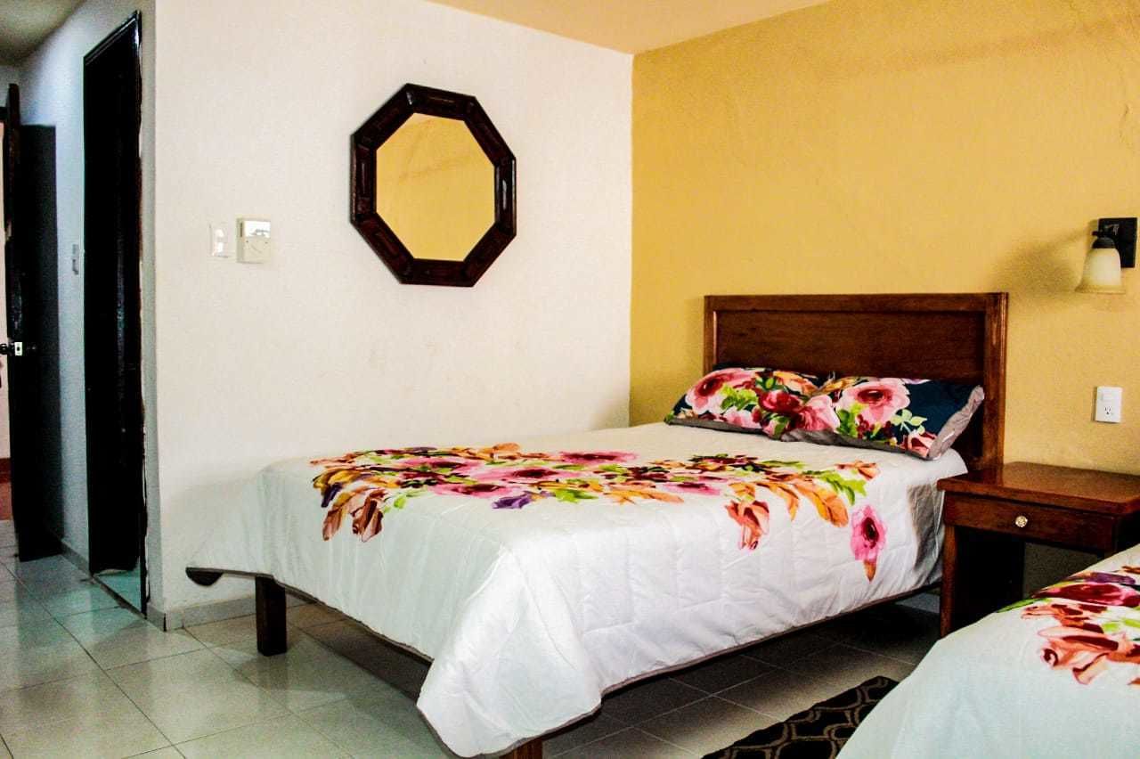 Een slaapkamer met een bed, nachtkastje, spiegel aan de muur en een lamp.