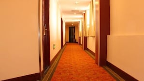 A hotel hallway with carpeted floors and walls, featuring doors and light fixtures. - Greentree Inn (Xuzhou)