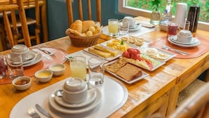 A breakfast buffet with various food items and beverages on a wooden table. - Ecocharme Pousada Do Marcilio (Fernando de Noronha)