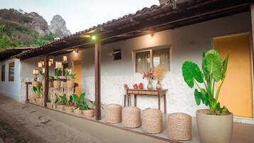 A building with a tiled roof, a stone pathway, and various potted plants.