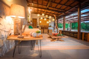 Un interior acogedor con techo de madera, un comedor con mesa y sillas, y vistas al exterior con vegetación.