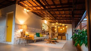 A cozy living area with a stone wall, a sofa, a dining table, and a hanging light fixture. - Ecocharme Pousada Do Marcilio (Fernando de Noronha)