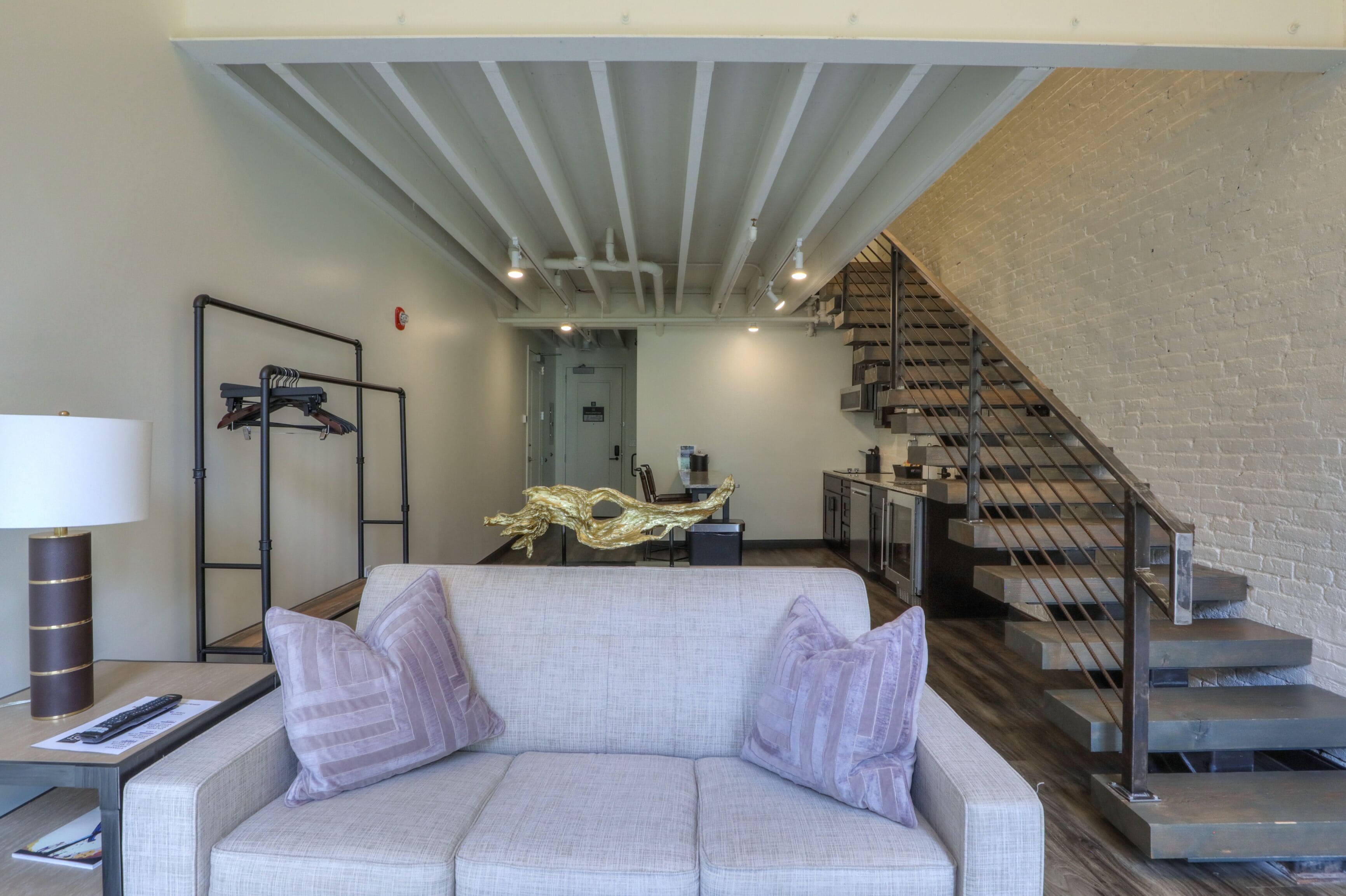 Un salon moderne avec un canapé, une lampe et un escalier menant à un niveau supérieur.