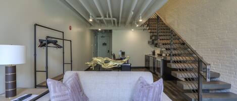 Un salon moderne avec un canapé, une lampe et un escalier menant à un niveau supérieur.