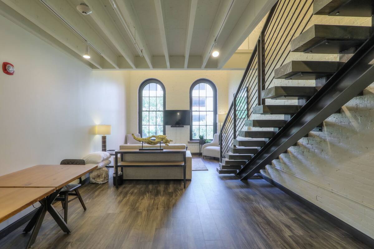 A modern interior with a wooden table, a sofa, and a staircase.