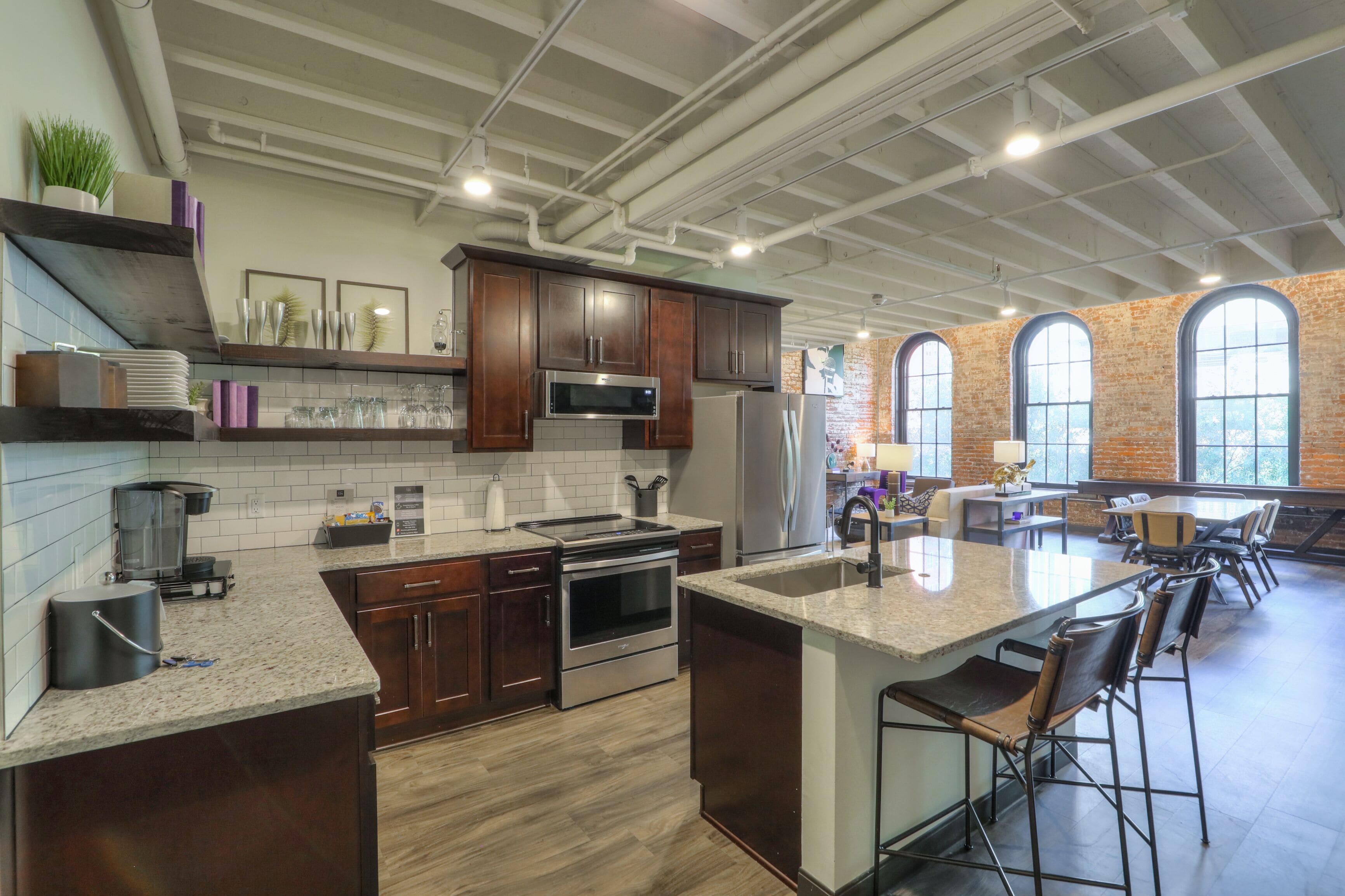 A modern kitchen with dark wood cabinets, stainless steel appliances, and a large island with bar stools.