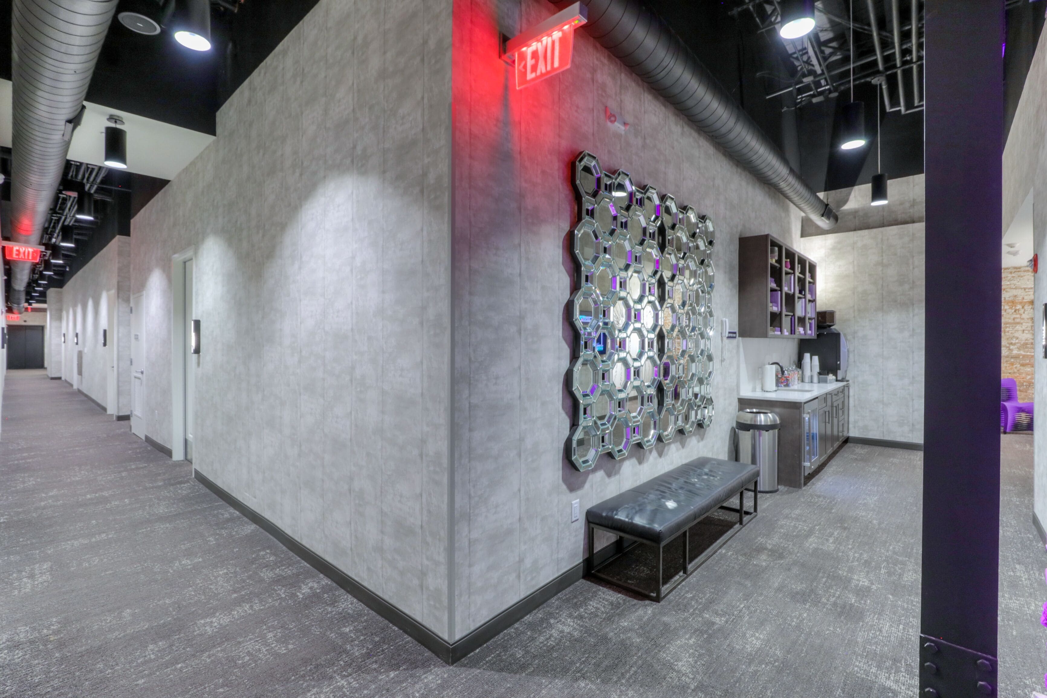 A modern interior with a grey wall, a bench, and a wall-mounted mirror display.