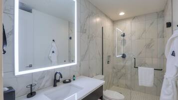 A modern bathroom with a large mirror, a sink, a toilet, and a shower area.