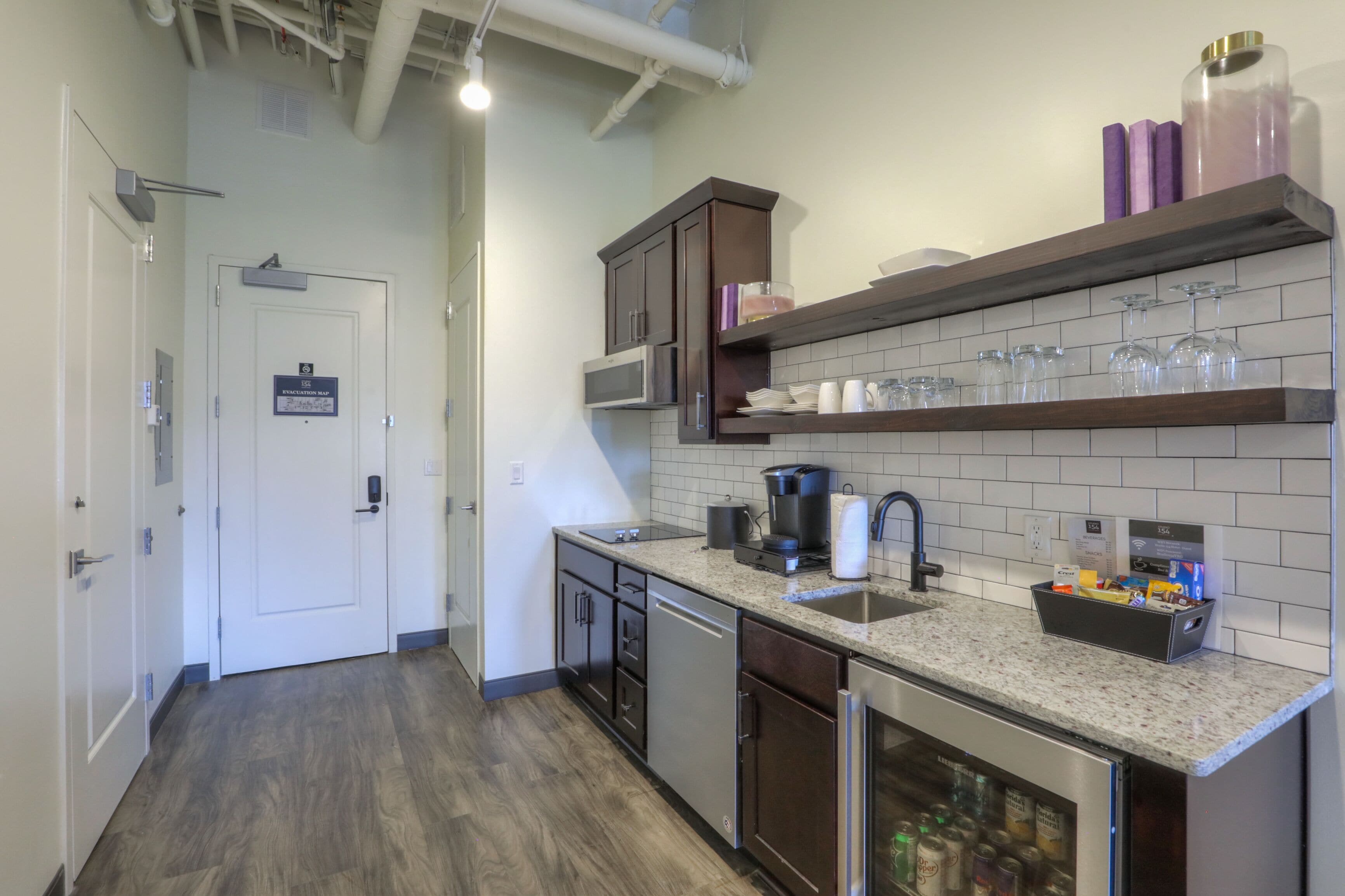 A modern kitchen with stainless steel appliances, a granite countertop, and a built-in dishwasher.