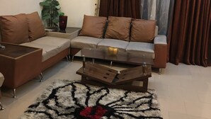Ein Wohnzimmer mit einer Eckcouch, einem Couchtisch und einem gemusterten Teppich.