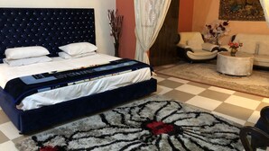 Ein Schlafzimmer mit einem großen Bett, einem Sofa, einem Couchtisch und einem gemusterten Teppich.