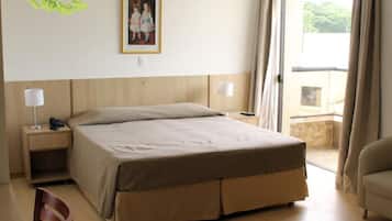 A hotel room with a bed, bedside tables, a chair, and a window with curtains.