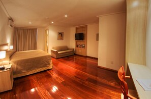 Een hotelkamer met een bed, een bank, een bureau en een televisie.