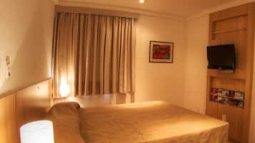 A hotel room with a bed, a TV, a lamp, and a painting on the wall.