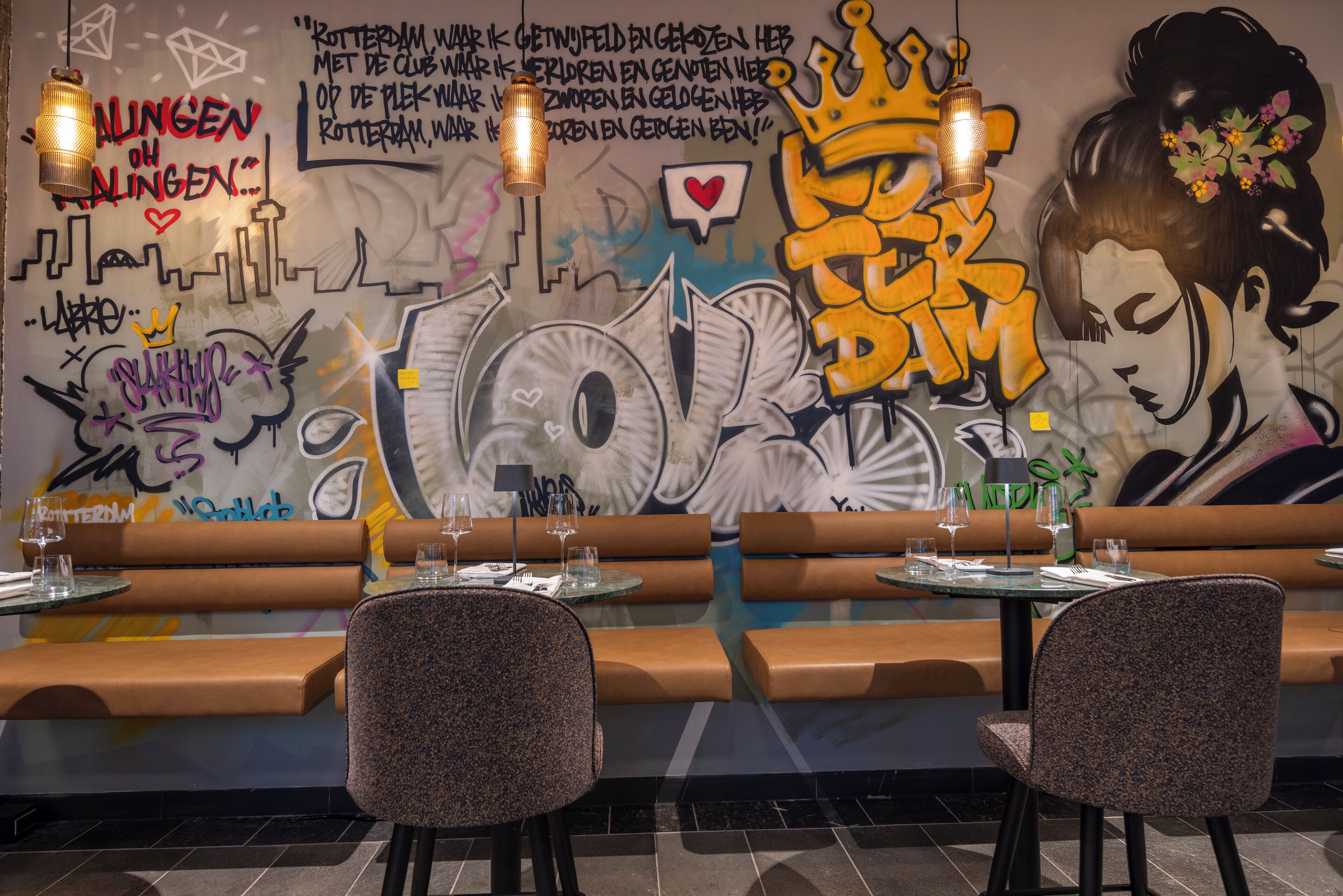 Een restaurantinterieur met graffiti op de muur, zitmogelijkheden en gedekte tafels.