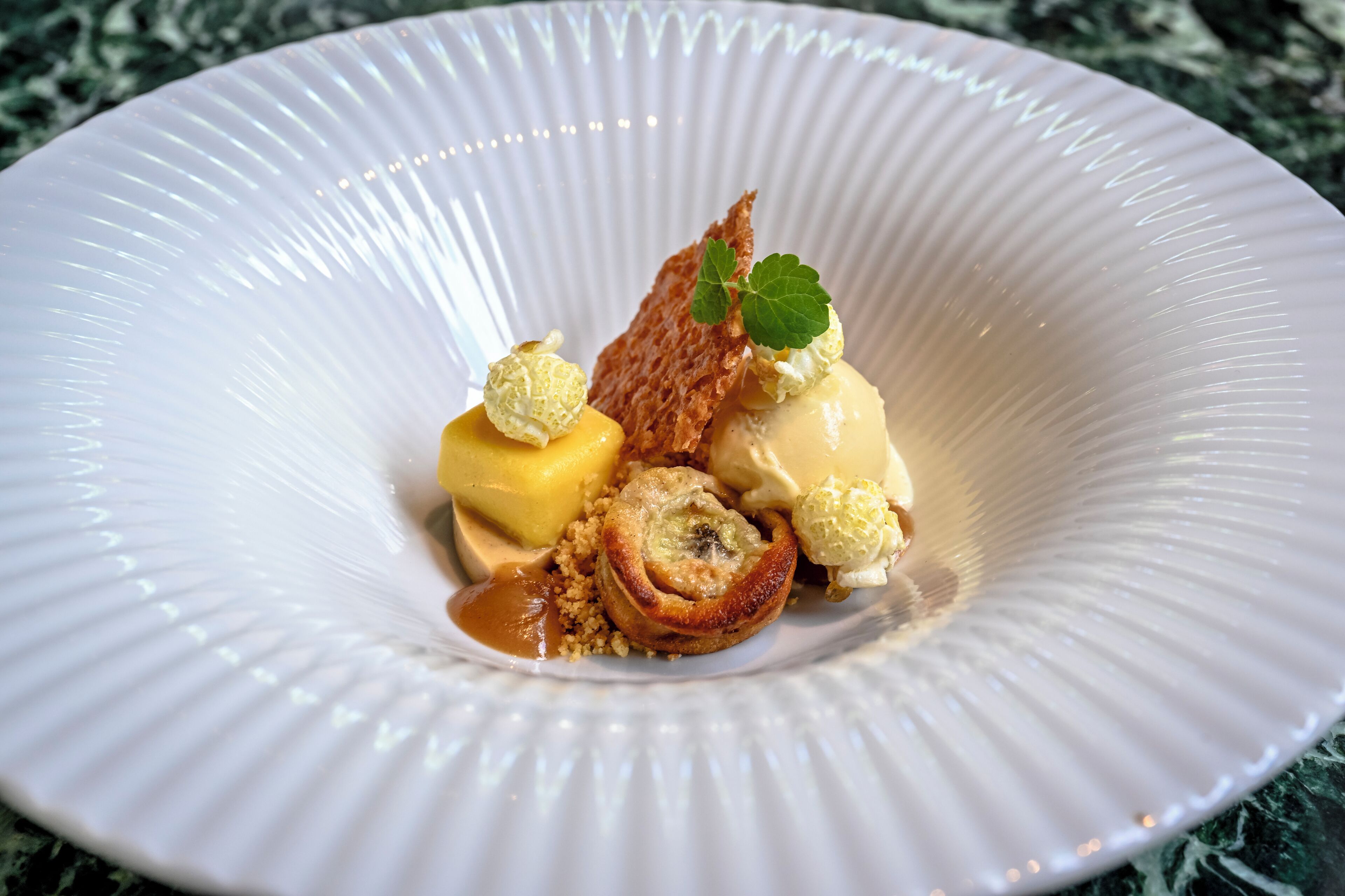 Un plato de postre con helado, caramelo y un pastel.