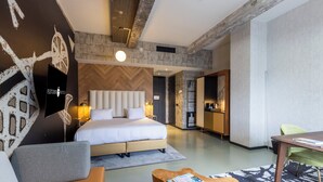Una habitación de hotel moderna con una cama grande, una mesa de centro de madera, un sofá y una mesa de comedor.
