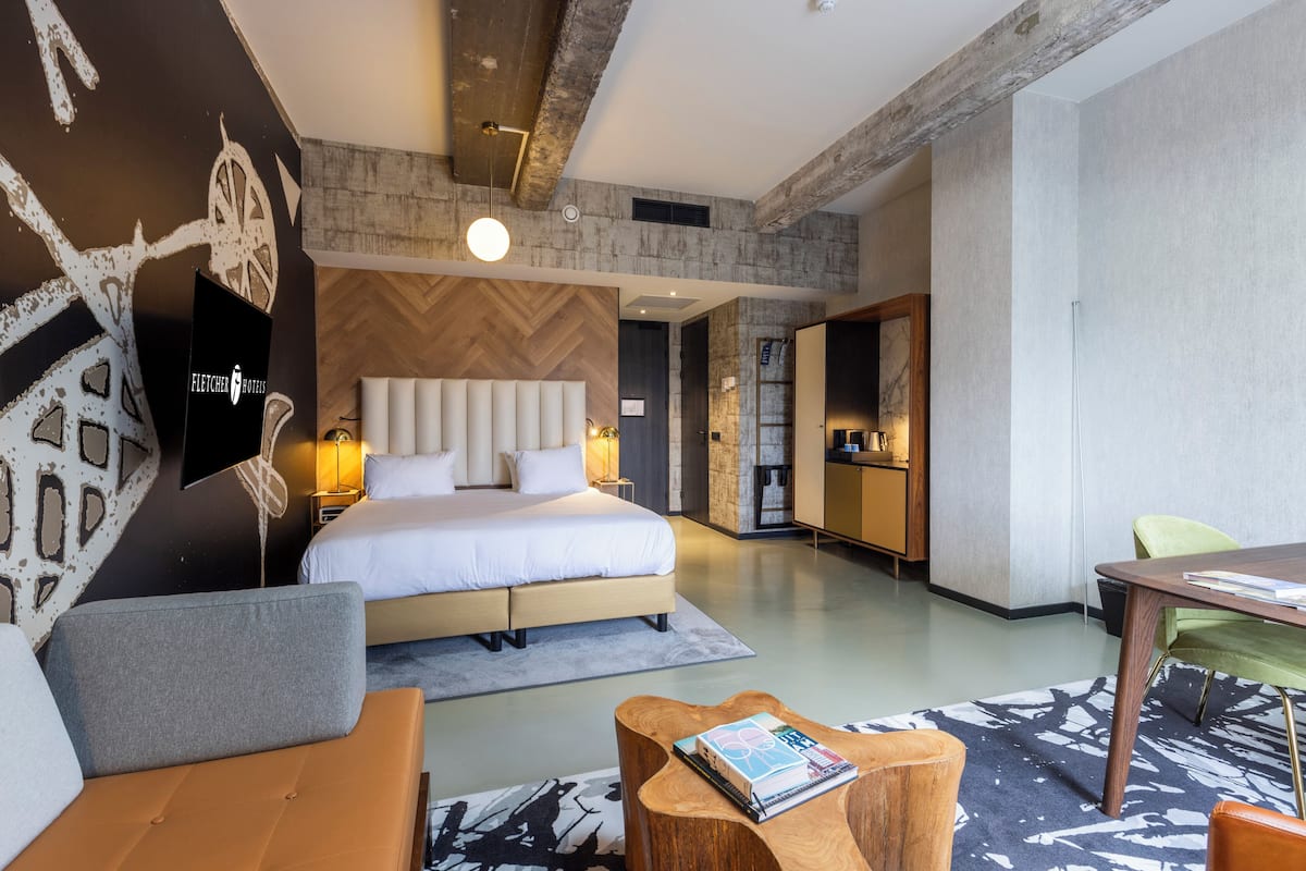 Une chambre d’hôtel moderne avec un grand lit, une table basse en bois, un canapé et une table à manger.
