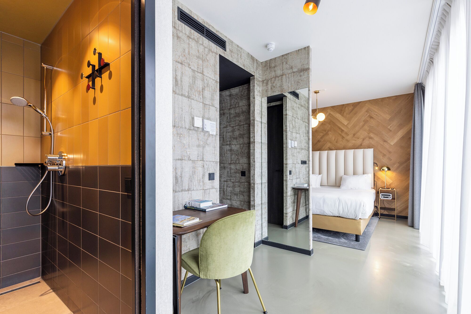 A modern hotel room with a shower, a desk, a bed, and a nightstand.