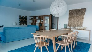 A modern living room with a blue sofa, wooden dining table, and chairs. - Mediterranean Villas (Santa Cruz)