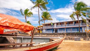A boat docked near a building with a balcony, palm trees, and a clear sky.