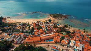 An aerial view of a coastal town with buildings, a beach, and a rocky island.