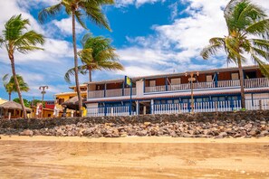 A beachfront hotel with a two-story structure, a stone wall in front, and palm trees. - Amendoeira Praia Hotel (Cairu)